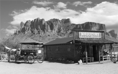 Old black and white Wild West Cowboy town with horse drawn carriage and mountains in background