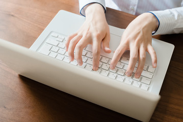 ラップトップのキーボードをタイピングする女性