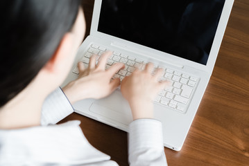 ラップトップのキーボードをタイピングする女性