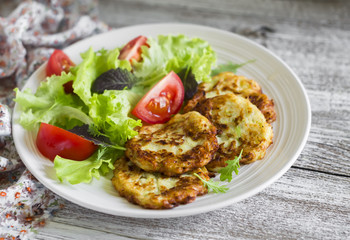 zucchini pancakes and fresh vegetable salad on white plate 