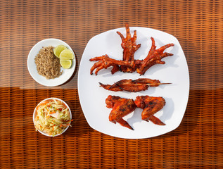 Grilled chicken on white plate with parsley, salad and beer outdoors