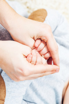 Mother and baby holding hands, making heart shape