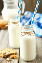 Two bottles of milk with striped straws and cookies 