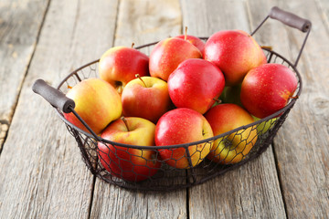 Red apples in basket on grey wooden background