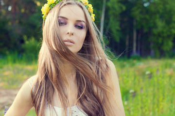 Naklejka premium beautiful sexy sweet girl with long hair and a wreath of yellow roses on his head in the field, the wind blowing her hair