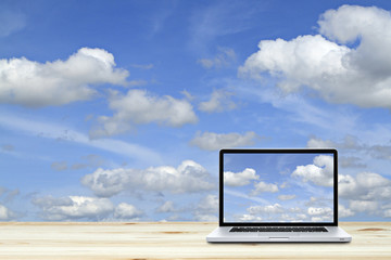 Laptop computer on wooden floor with sky  background. White screen