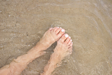 Female feet in water on beach.