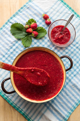 Homemade strawberry jam (marmelade) cooking. Large pot with hot jam and fresh strawberries