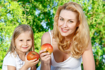 Mother and daughter sitting on cover with apples 