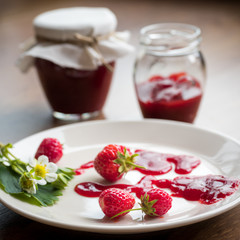 Homemade strawberry jam (marmelade) in jars on wooden background.