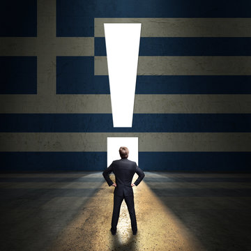 Geschäftsmann steht vor leuchtendem Ausrufezeichen-Portal in einer Griechenland-Wand 
