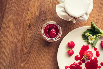 Homemade strawberry jam (marmelade) in jars on wooden background.