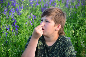 Fototapeta premium teen boy with allergies in flowering herbs
