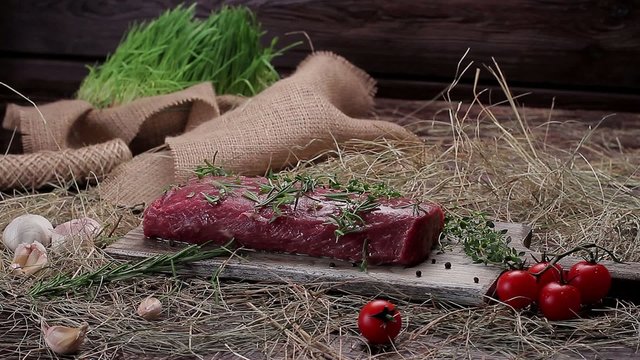 Raw beef marinated in spices. Meat with tomatoes and garlic on the hay.