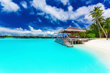 Jetty and palm trees with steps into tropical blue lagoon