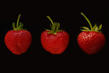 three strawberries on black background