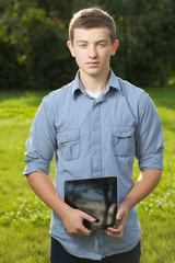 boy holding tablet PC on green grass lawn with copy space