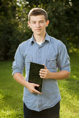 boy holding tablet PC on green grass lawn