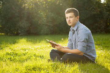 boy holding tablet PC on green grass lawn with copy space