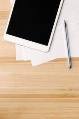 digital tablet and paper on wooden table