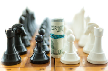 twisted dollar bills between white and black chess pieces © Kyrylo Ryzhov