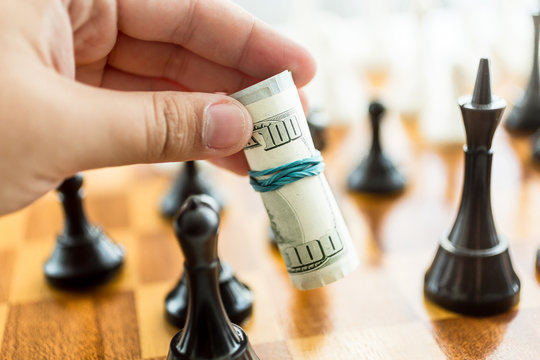 Conceptual Photo Of Man Making Move At Chess Game With Dollar Bi