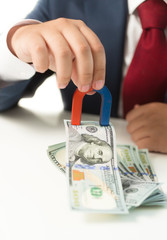 businessman holding magnet and drawing money from the table