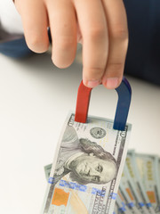 Closeup of male hand holding magnet and pulling money from stack