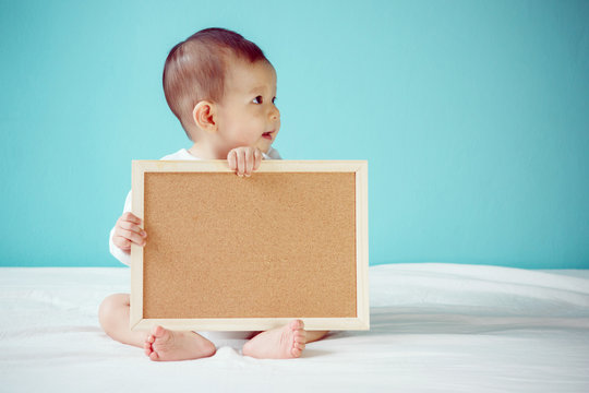 Infant child holding empty board, studio shot