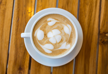 Cup of coffee with heart pattern in a white cup on wood table