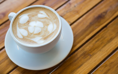 Cup of coffee with heart pattern in a white cup on wood table