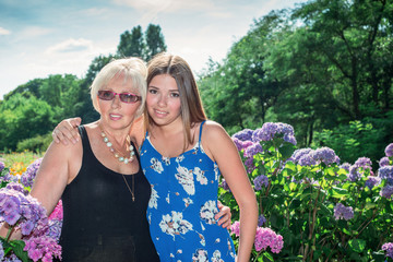 Two women of different generations standing near flowers hydrangeas. Mother and daughter. Grandmother and granddaughter.