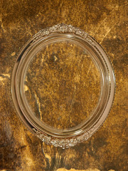 Golden oval photo frame on grungy wall.