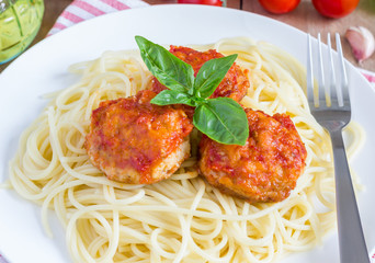 Meatballs in tomato sauce with spaghetti on a white plate