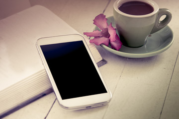 Fototapeta na wymiar smart phone,cellphone on open book with cup of coffee in vintage