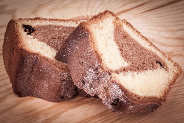 Two slices of cocoa cake on a wooden background.