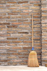 Household Broom For Floor Cleaning Leaning on Brick Wall