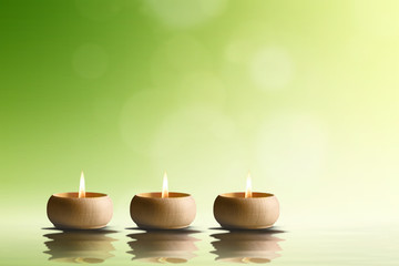Obraz na płótnie Canvas Spa concept. Three candles on green background.