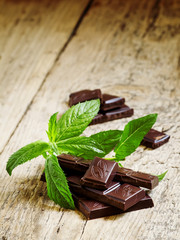 Dark chocolate with mint on an old wooden table, selective focus