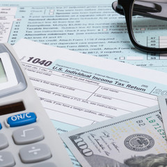 US 1040 Tax Form, calculator, glasses and dollars - close up