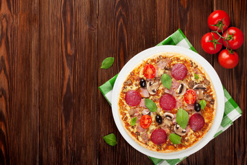Italian pizza with pepperoni, tomatoes, olives and basil