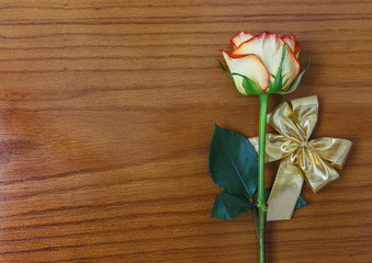 Rose and gold decorative bow on the wooden background