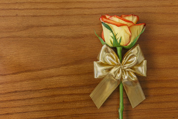 Fototapeta premium Rose and gold decorative bow on the wooden background