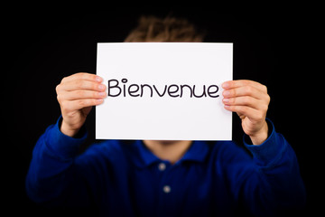 Child holding sign with French word Bienvenue - Welcome