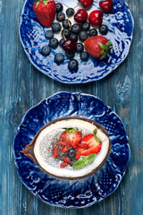 Chia seeds coconut pudding with berries on a blue background. top view