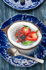 Chia seeds coconut pudding with berries on a blue background. top view