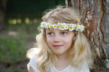 smiling blond girl with big blue eyes and with daisies on head