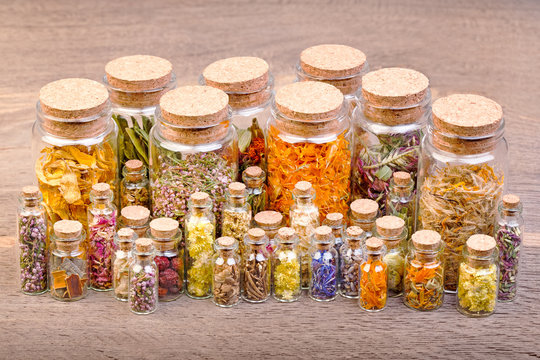 Various kinds of tea and healing herbs in clear glass bottles on