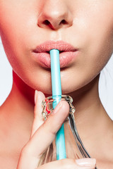 Сlose-up of a girl with a bottle of soda and drinking straw