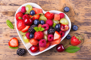 Fruit salad in heart shaped bowl - healthy eating - obrazy, fototapety, plakaty